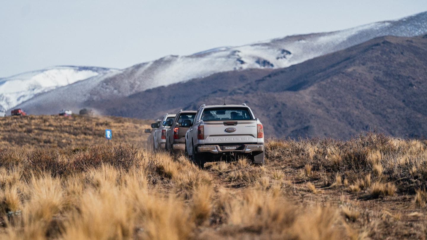 Camionetas Ranger en camino de tierra con montaña de fondo
